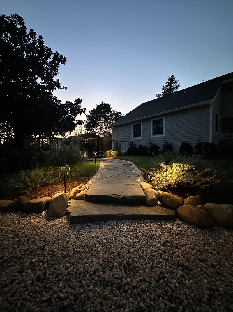 Path lights along a walkway to a house at dusk