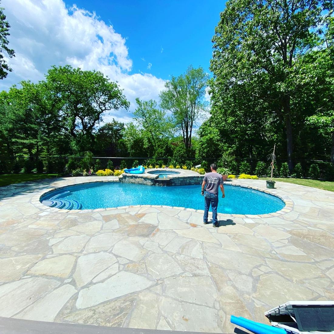 Pool and stone patio with lawn and trees