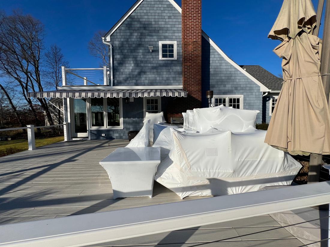 Patio furniture shrink-wrapped for winter on a deck